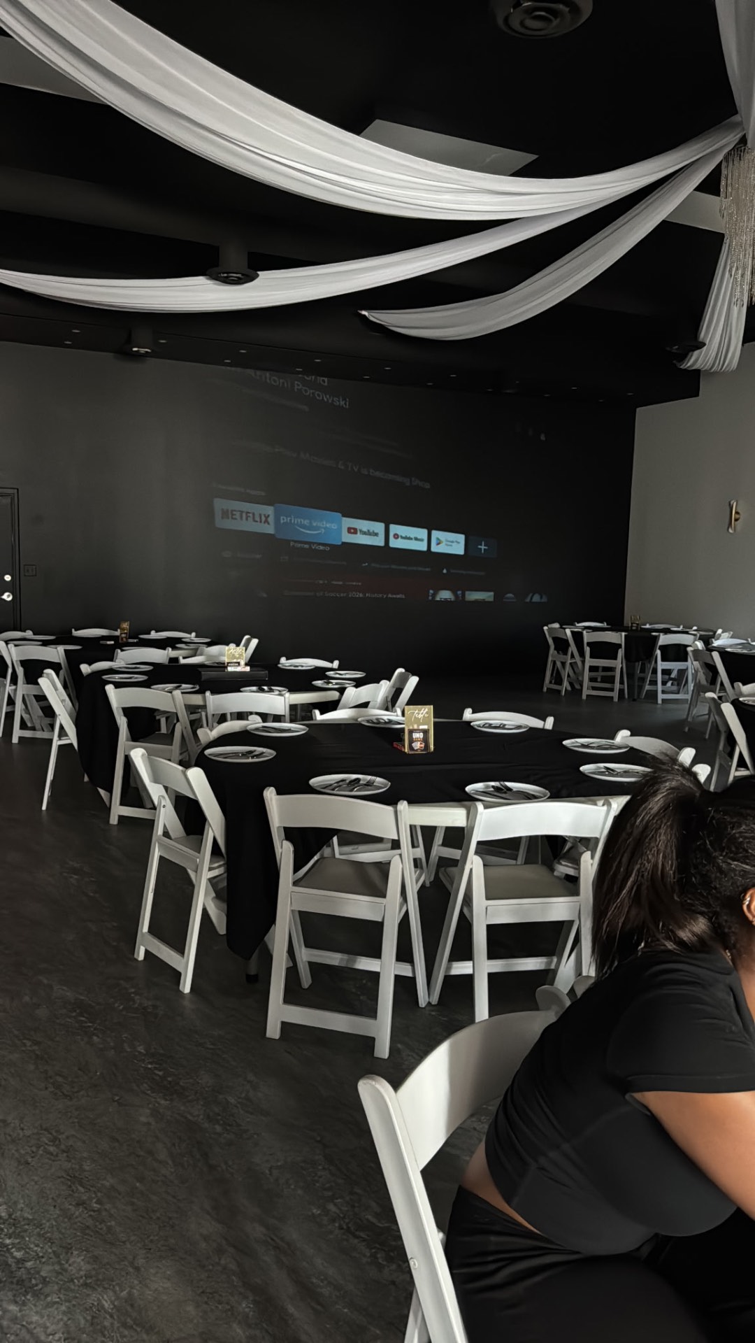 Black-linen round tables set with draped ceiling and projector screen