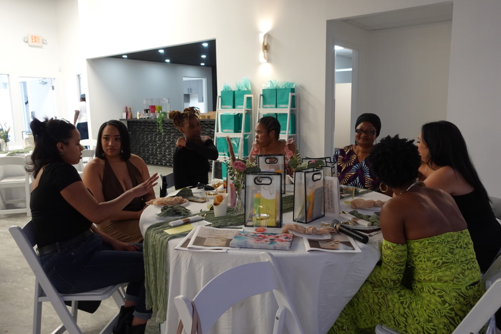 Women in conversation around a table set with sage linen and florals
