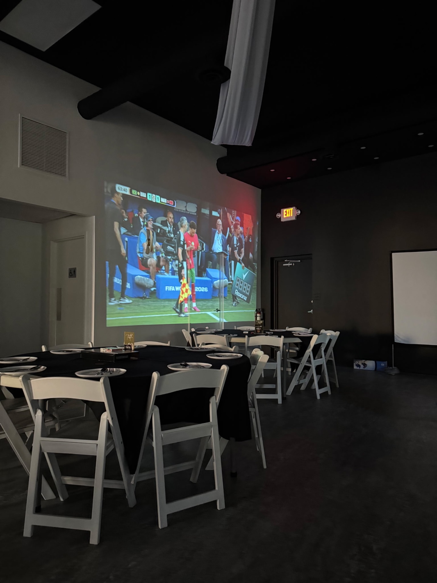 Football projected on the wall above set tables in the lounge
